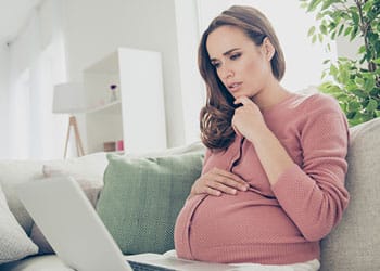 Pregnant woman reading an adoption blog on her laptop