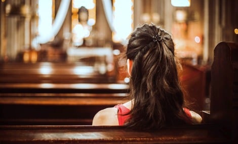 Woman seated in a church pew facing away from the camera