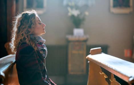 Hopeful adoptive mother praying in church