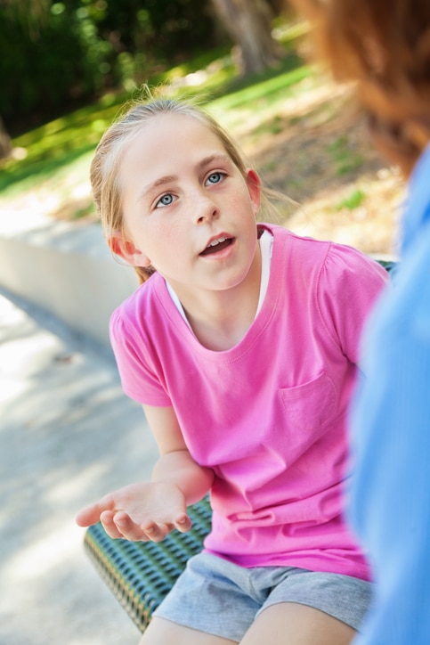 Little girl taking to mom outdoors