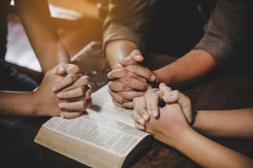 Cropped photo of a group of three women praying together