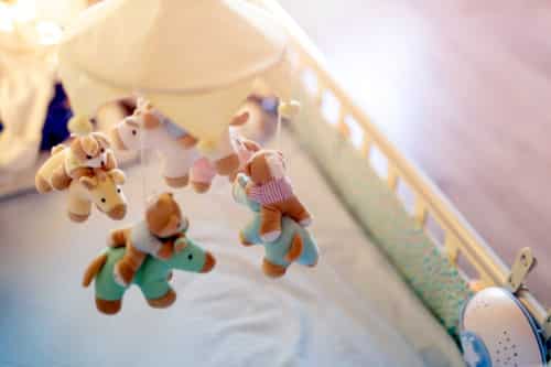 Close-up baby crib with musical animal mobile at nursery room