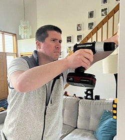Tyler drilling a hole into the wall of their living room