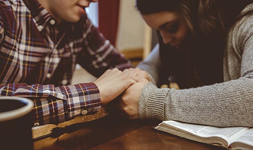 Couple studying the Bible and praying at home together