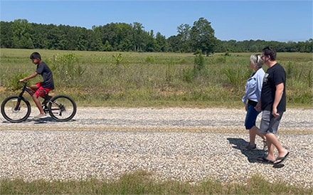 Brice and Rachael walking together while their son bikes ahead