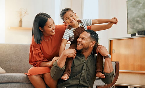 Happy adoptive couple playing with their son in their living room