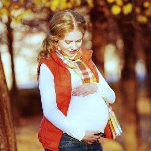 Happy pregnant woman on autumn walk in nature