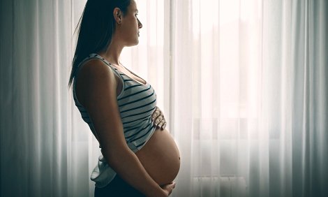 pregnant women belly in front of a curtain while thinking about adoption or parenting