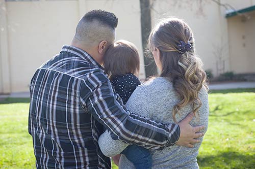 Happy couple embrace their daughter who joined the family through Christian adoption