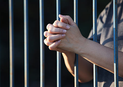 Female hands praying in jail 