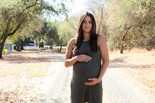 Pregnant woman pauses during a trail walk