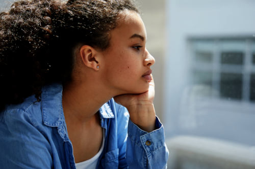 Side view of sad young woman looking out of the window