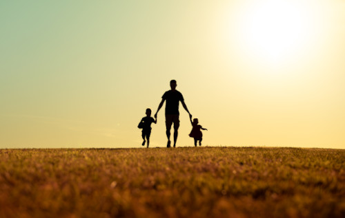 Father walking with his kids in the park at sunset