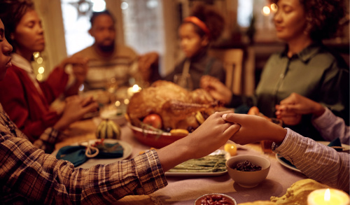 Family holding hands while praying before dinner on Thanksgiving