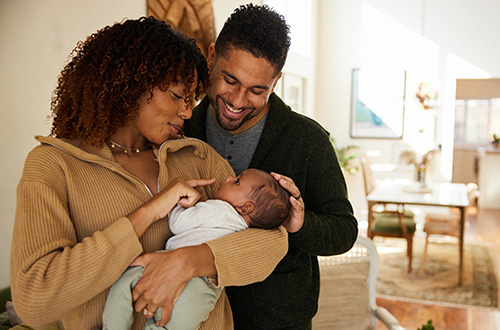 Loving adoptive mother and father holding their baby boy and smiling